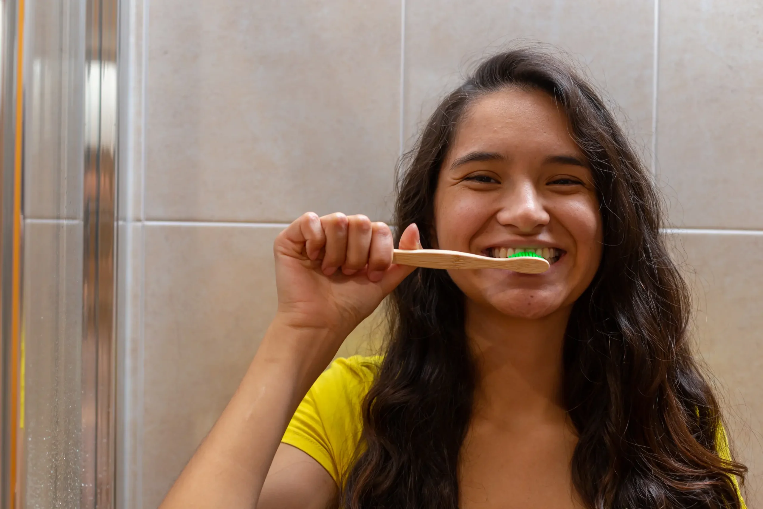 Chica cepillandose los dientes con un cepillo de bambu